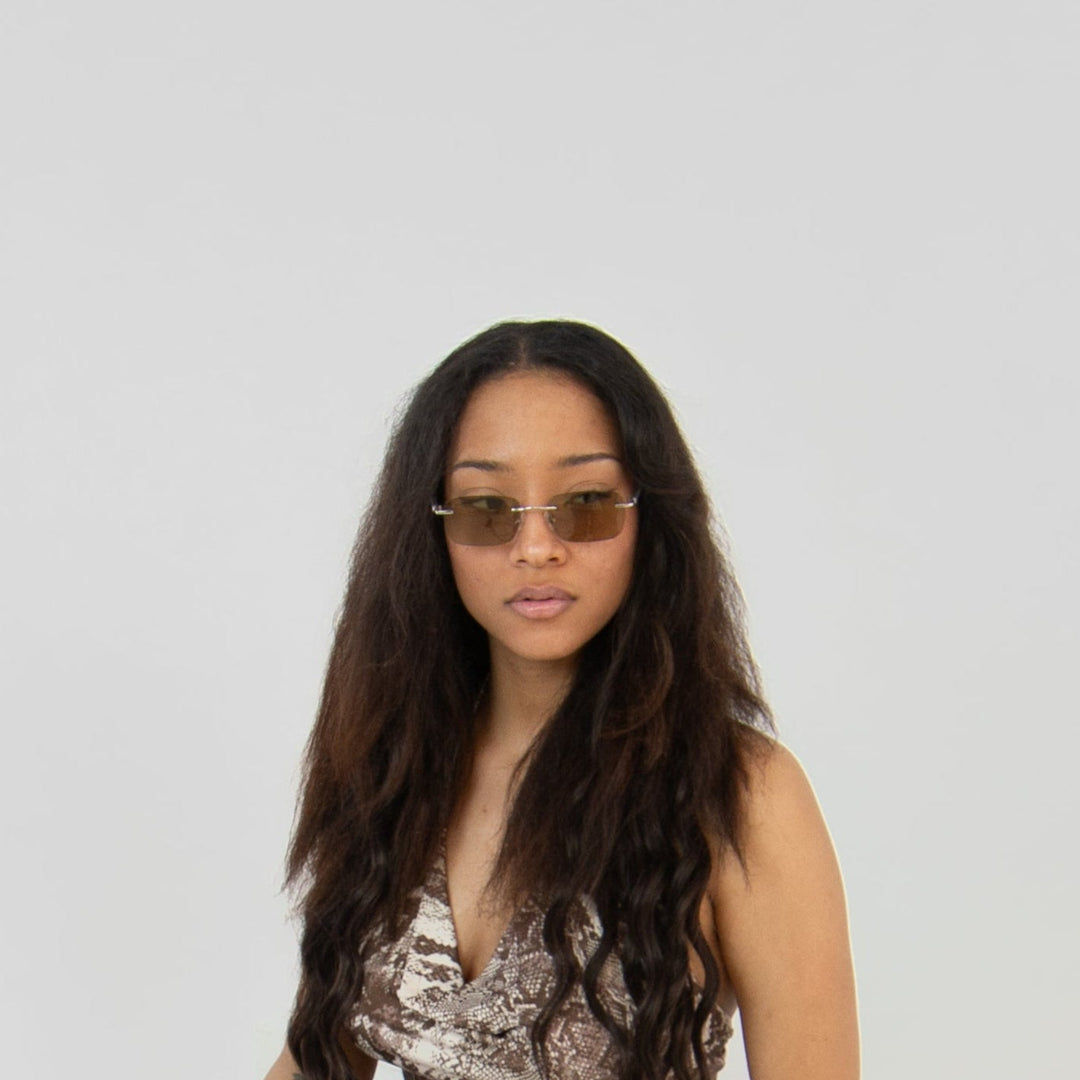 Model mit Asteria Midnight Brille in Gold – Unisex-Design im minimalistischen Editorial-Setting, mit getönten Gläsern.